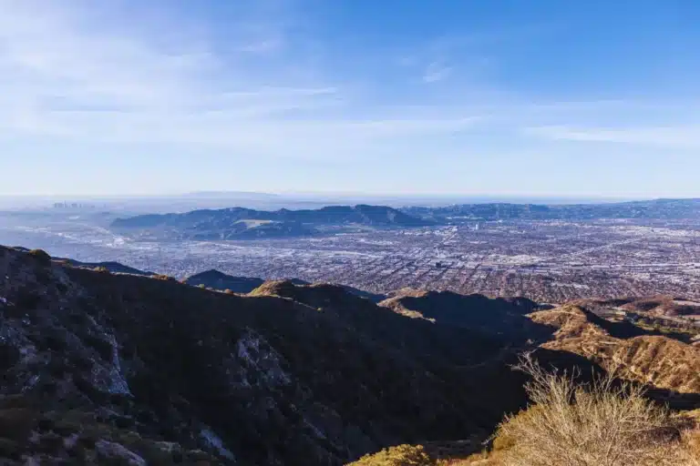 Aerial view of Burbank, California from the mountains, showing the city layout and Los Angeles skyline in the distance.