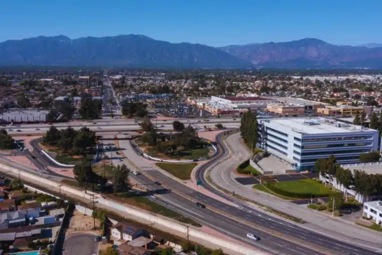 Modern building in El Monte, California surrounded by palm trees and clear skies with mountains in the distance.
