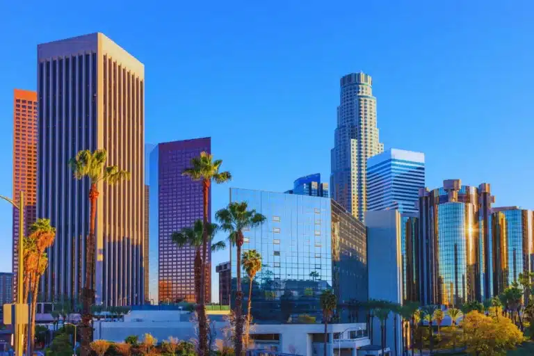 Modern skyscrapers and palm trees in downtown Los Angeles under a bright blue sky, representing the nearby South Gate area.